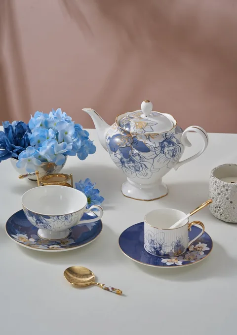 A blue and white ceramic tea set arranged with hydrangeas in a soft interior setting.
