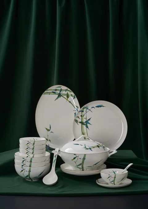 A coordinated bamboo-pattern ceramic dinnerware set against a deep green backdrop.