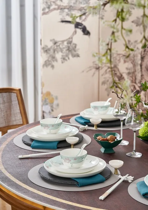 A complete dining scene with stacked floral ceramic plates, bowls, glasses and table accessories.