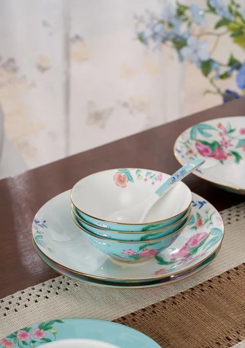 A close view of nested floral ceramic bowls and plates in a softly lit setting.