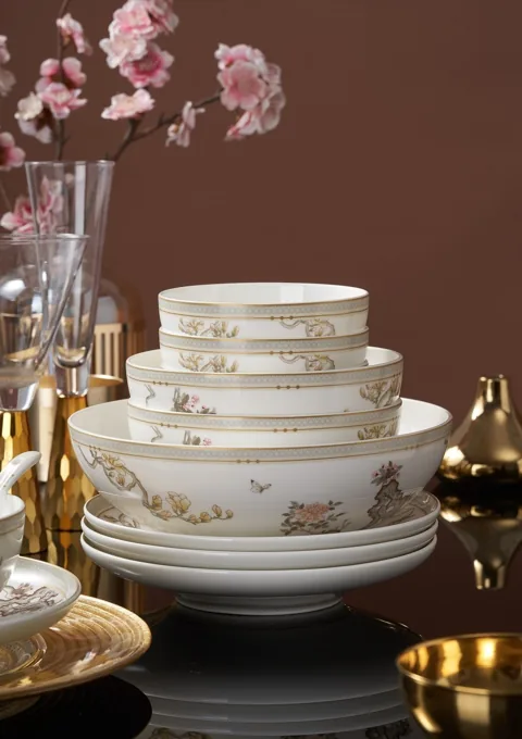 A coordinated stack of patterned ceramic bowls and plates with warm decorative accents.