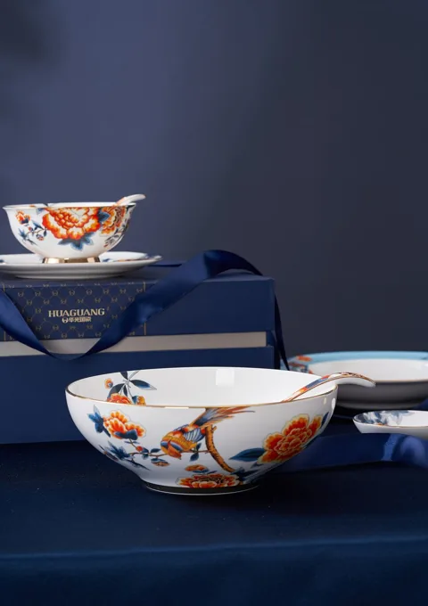 Decorated ceramic bowls displayed with coordinated packaging on a deep blue surface.