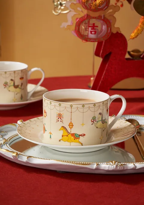 An illustrated ceramic cup and saucer with warm festive props and coordinated packaging.