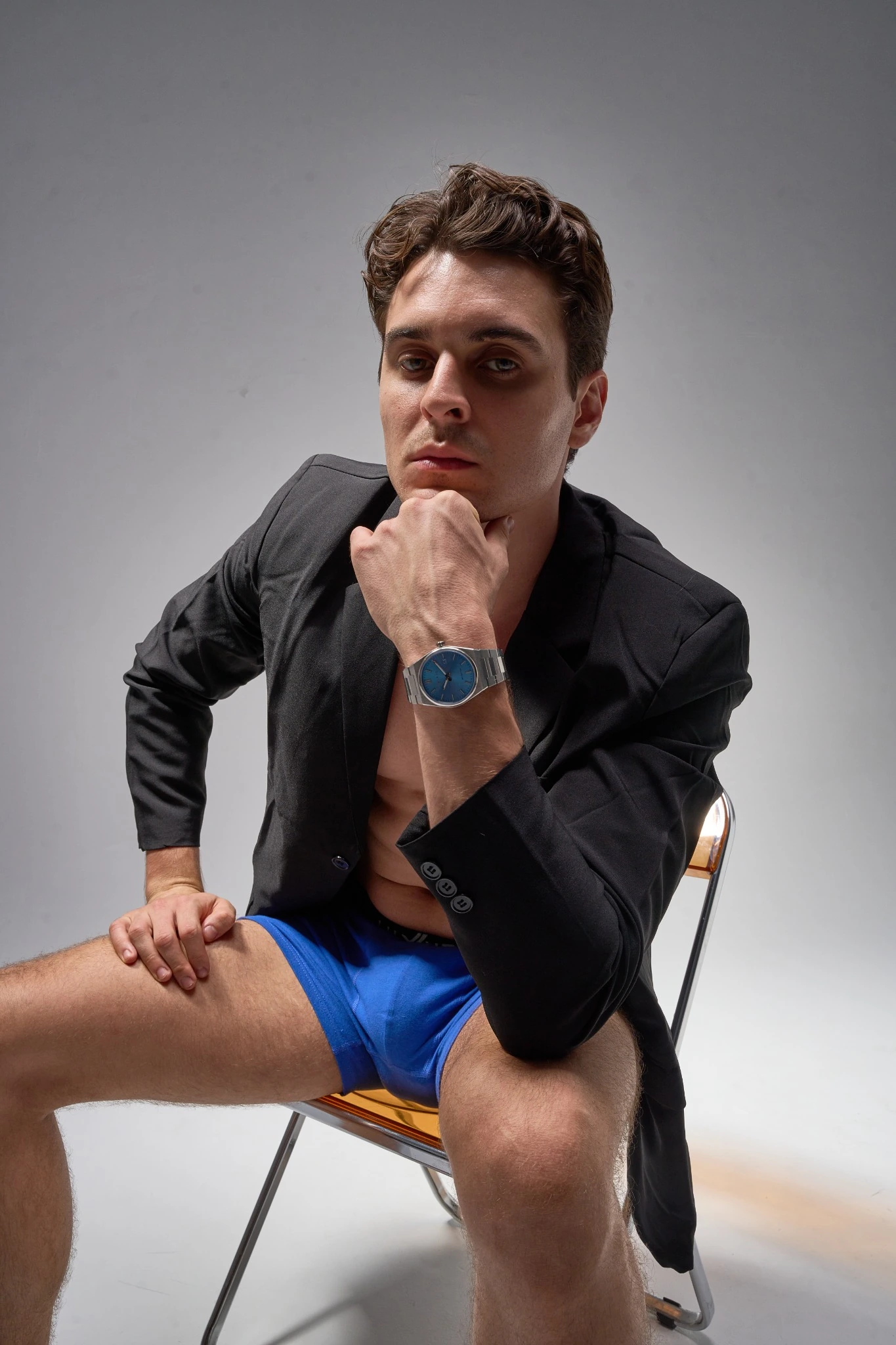 A male model wearing a blue-dial watch and a black blazer.