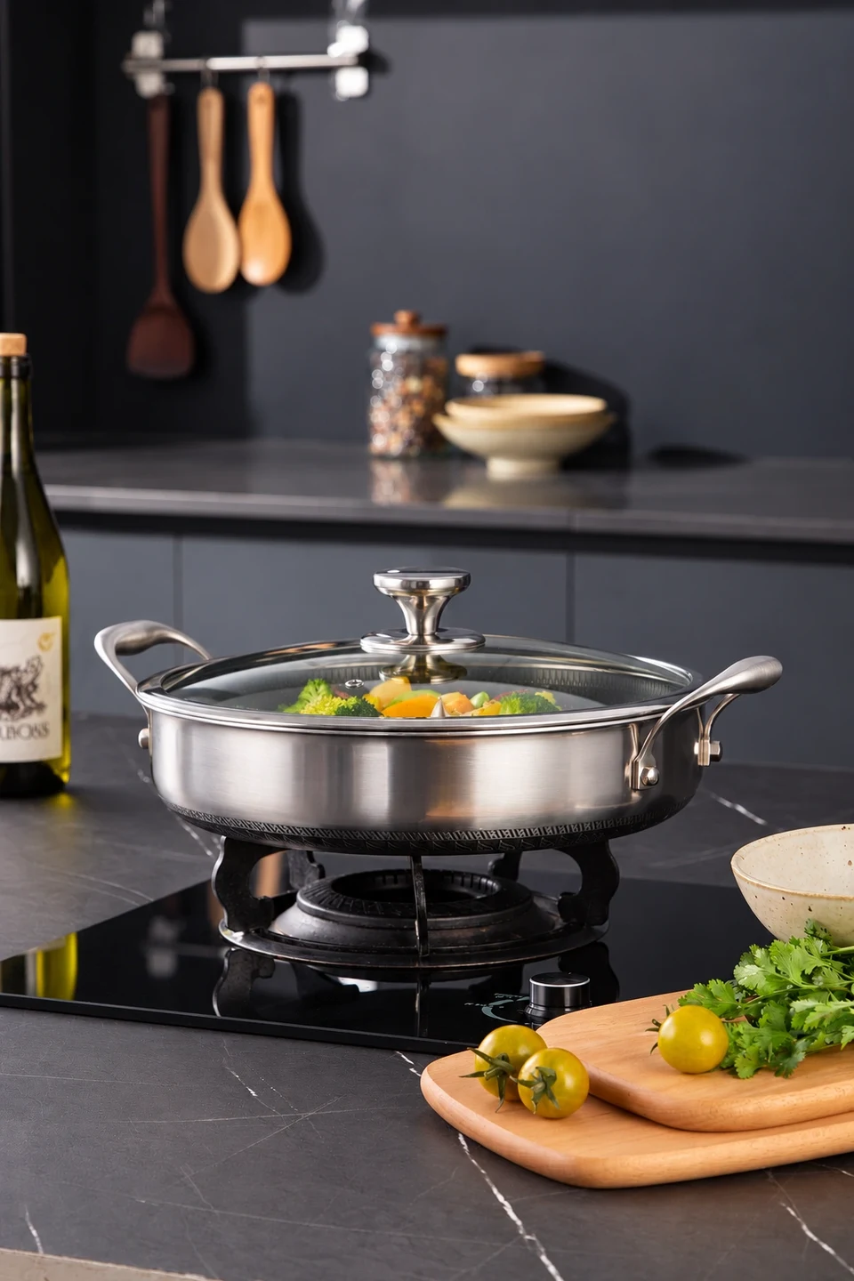 A stainless steel pan with vegetables on a stovetop in a dark kitchen.