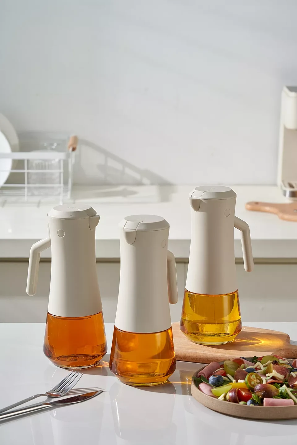 Three oil dispensers shown completely, with lids, handles and glass bases visible.