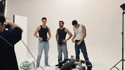 A photographer directing three models during a studio fashion shoot.