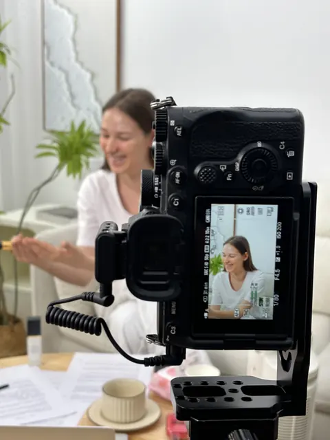 A camera filming a model with a product in a styled interior scene.
