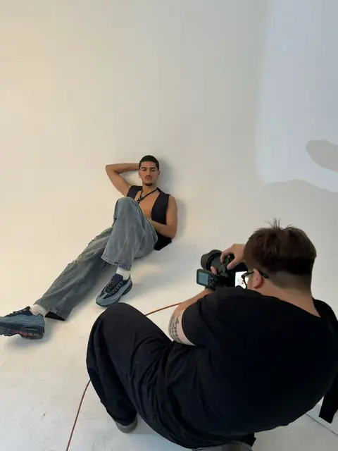 A photographer framing a seated model against a light studio background.