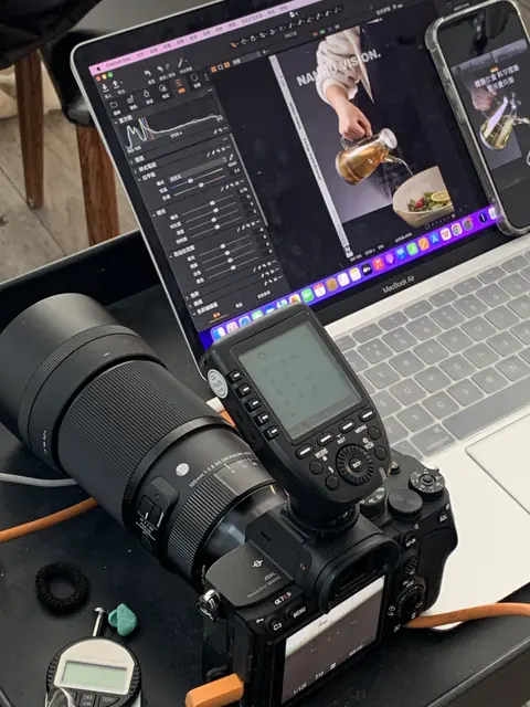 A camera beside a laptop displaying close-up product photography during a studio shoot.