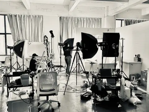 A black-and-white behind-the-scenes view of cameras, lighting and the production team.