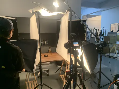 A studio tabletop surrounded by lighting, diffusion and camera equipment.